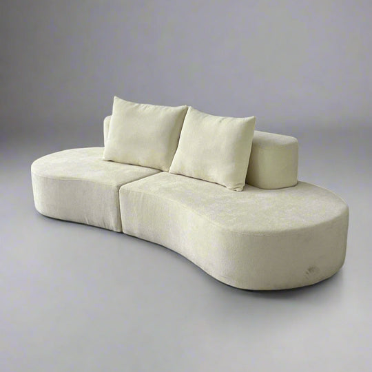 A beige crescent-shaped lounge sofa with plush cushions and a soft fabric cover.