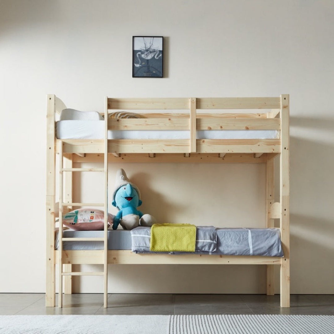 A single-over-single PineFlex bunk bed made of natural solid pine wood, with a ladder on the left side and a guardrail on the top bunk. The bed is set against a wall with a picture hanging above it, and a plush toy is seated on the lower bed.