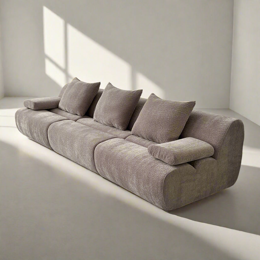A modern gray modular sofa with plush cushions and an ultra-soft textured fabric in a well-lit room.